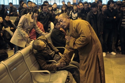 24. Un calugar se roaga pentru un barbat in varsta care a murit subit in timp ce se astepta un tren in gara din Shanxi Taiyuan, China.